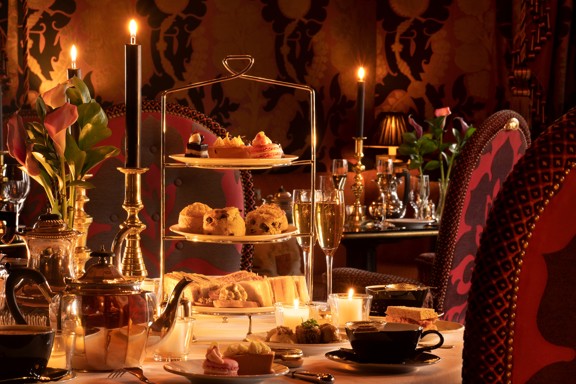 Rhurbarb Edinburgh restaurant table set for luxury afternoon tea with a three-tier stand of pastries, scones, and sandwiches, teapot, teacups, champagne glasses, candles, and flowers