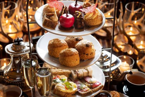 Three-tier stand of elegant vegetarian afternoon tea at Prestonfield House, Edinburgh, featuring savouries, scones and pâtisserie in a luxurious candlelit setting