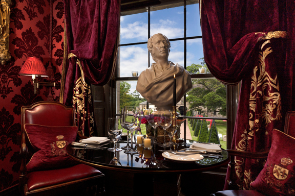 Set table with marble bust and red velvet decor in The Salon Privee small private dining room at Prestonfield House Edinburgh
